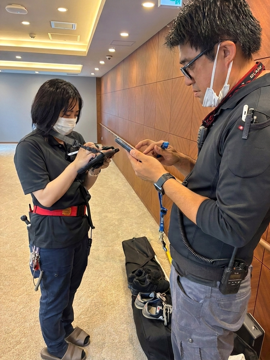 点検先の現場でメンバーとタブレット端末を確認し合う様子