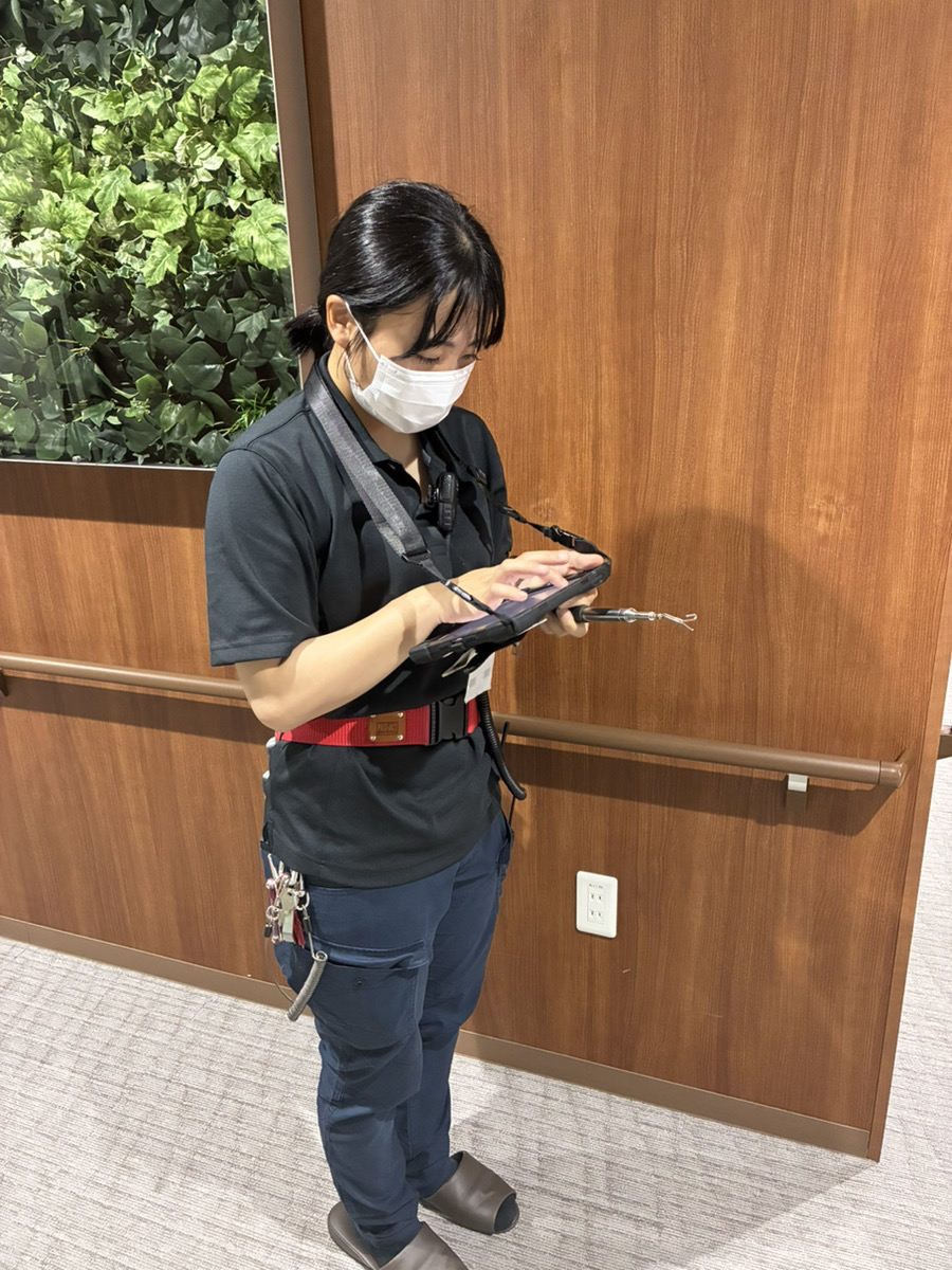 タブレット端末で点検記録を入力する女性消防設備士の草地