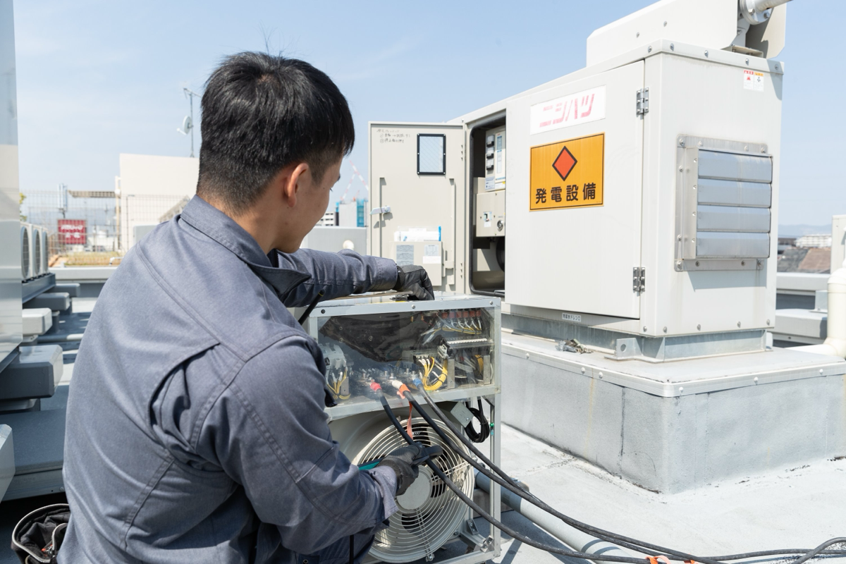 非常用自家発電設備に疑似負荷試験機を接続して点検する作業員